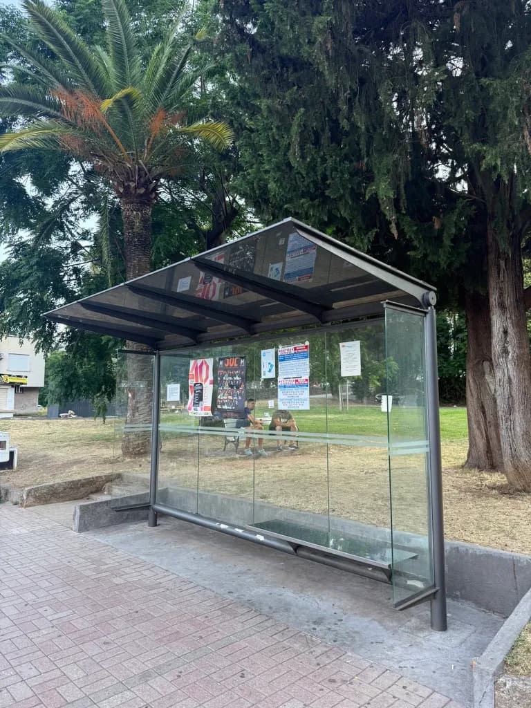 A Mediteran Express bus stop on the Budva Riviera: a glass shelter with a bench and the timetables posted inside.