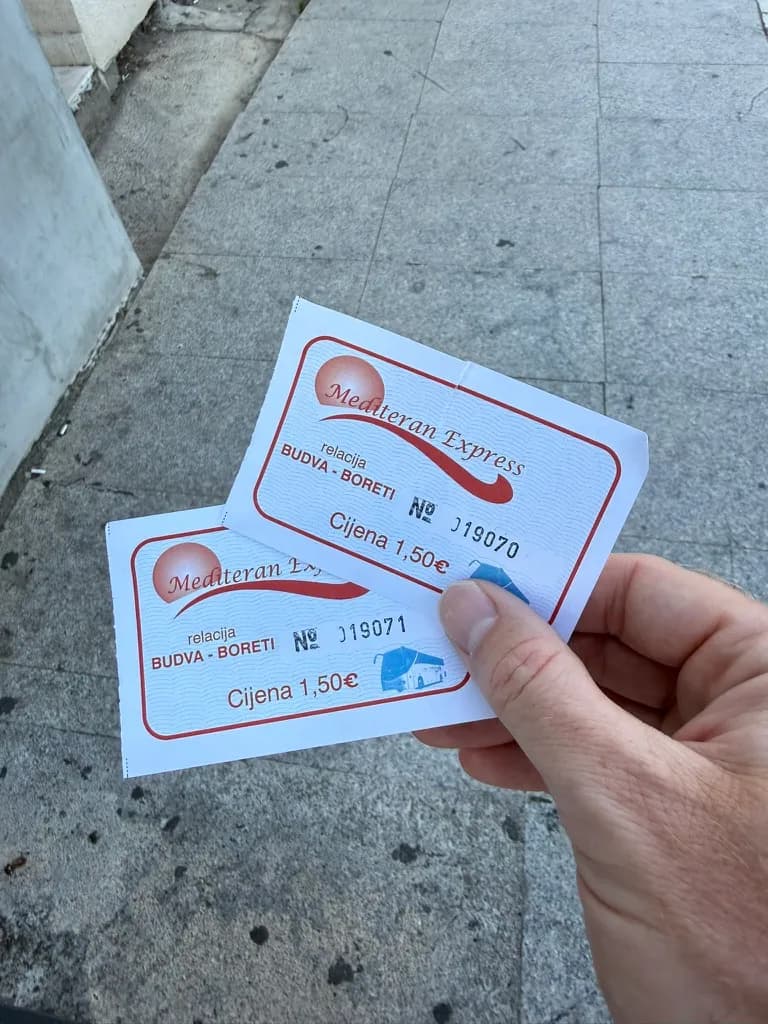 Two paper Mediteran Express bus tickets for Budva–Boreti at €1.50 each, bought with cash from the seller at the stop.